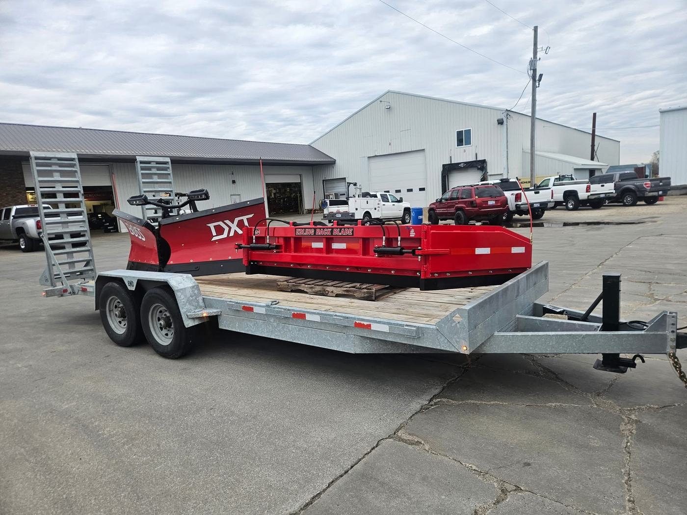 Custom Klean snow plow blade and back blade equipment staged on a trailer