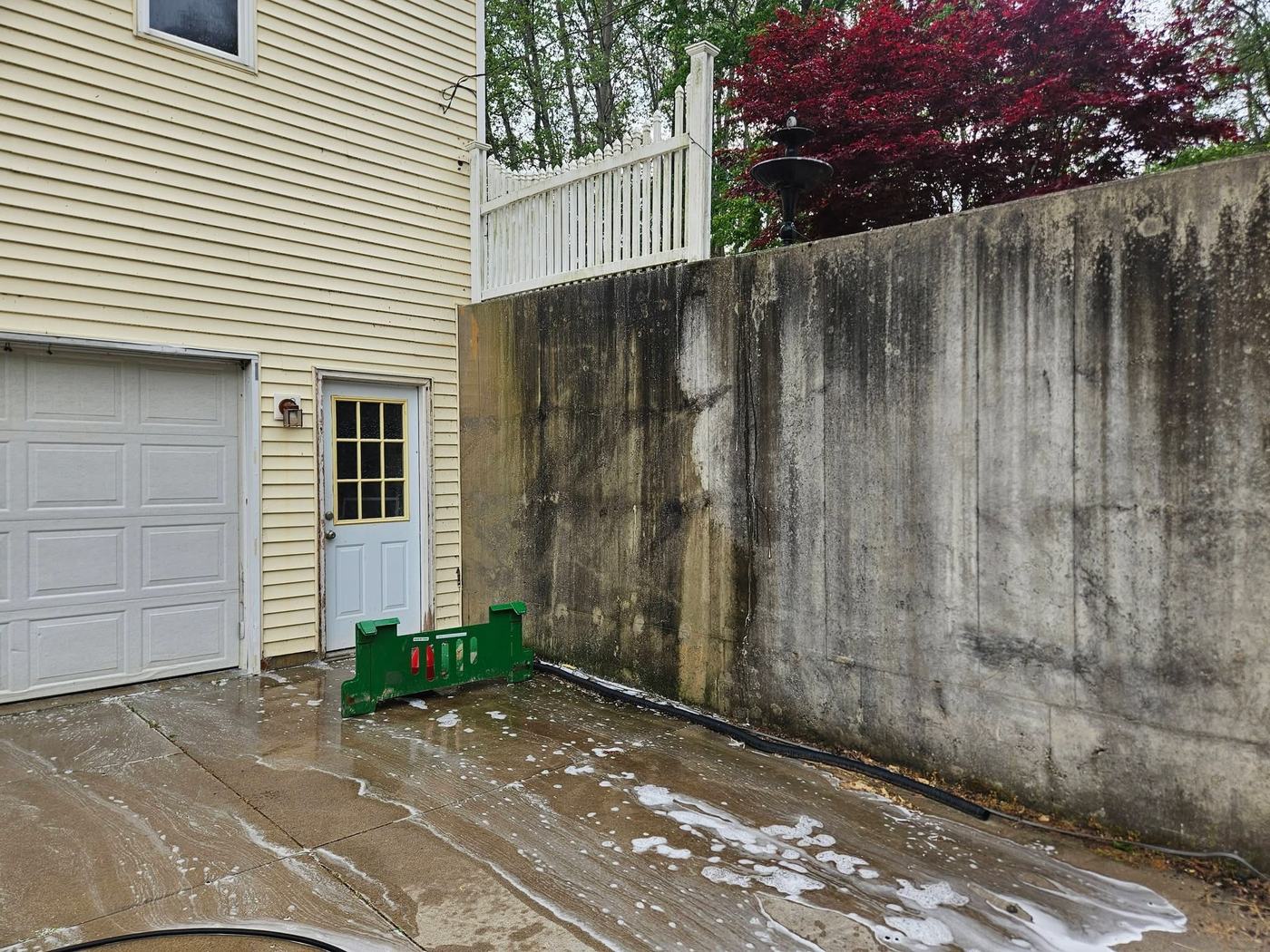 Concrete retaining wall heavily stained with black mold and algae buildup, before cleaning